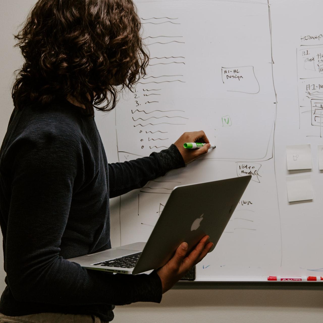 man wearing gray polo shirt beside dry-erase board