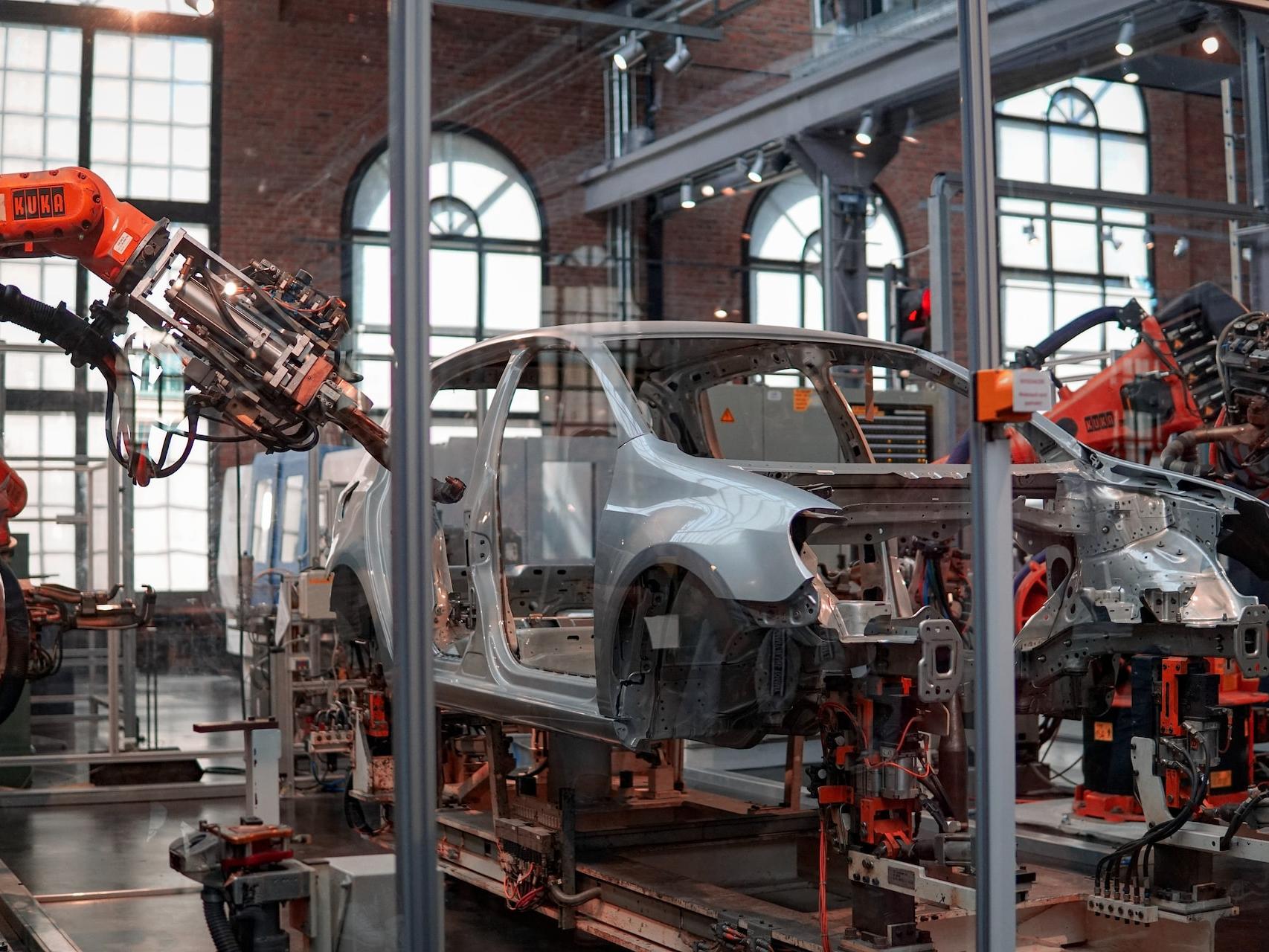 Nội thất, gia dụng gray vehicle being fixed inside factory using robot machines