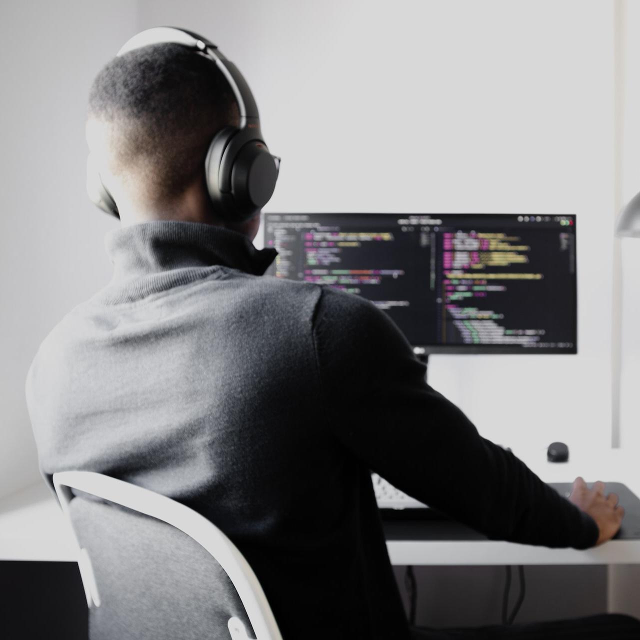man in black long sleeve shirt wearing black headphones sitting on chair